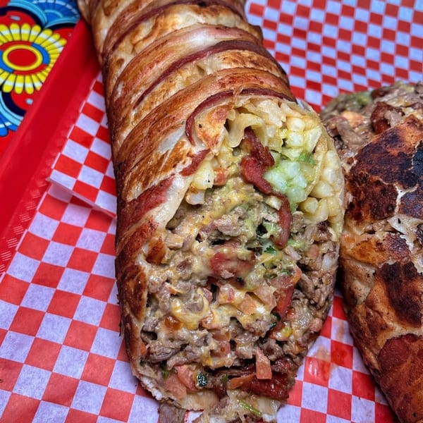 A bacon-wrapped burrito from Sayulitas, cut open to reveal carne asada, cheese, and guacamole.