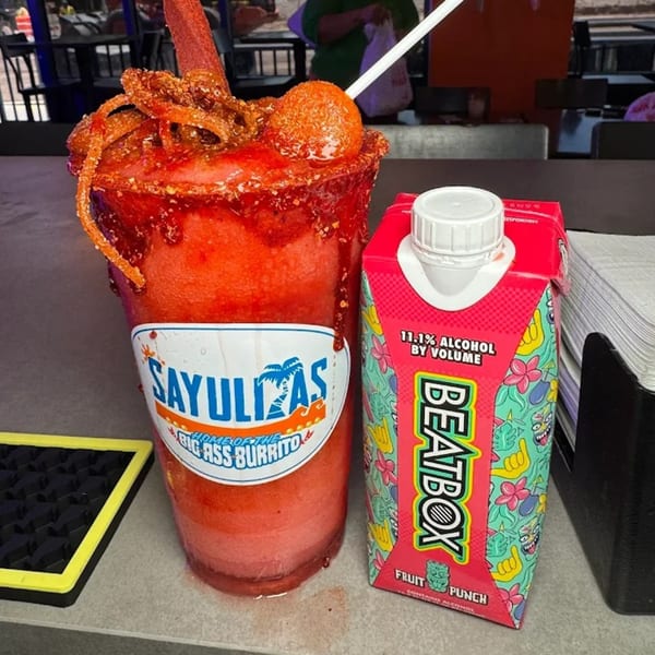 A Sayulitas branded mangonada with a Beatbox Fruit Punch carton on a counter.