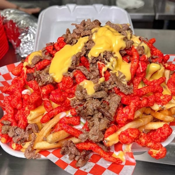 Sayulitas' loaded fries with carne asada, nacho cheese, and hot Cheetos in a white container.