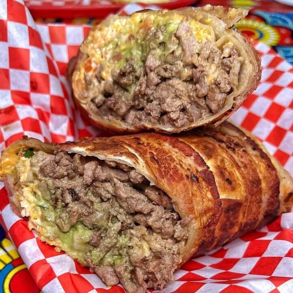Two halves of a crispy, golden-brown Mexican burrito, revealing a hearty filling of meat and guacamole.