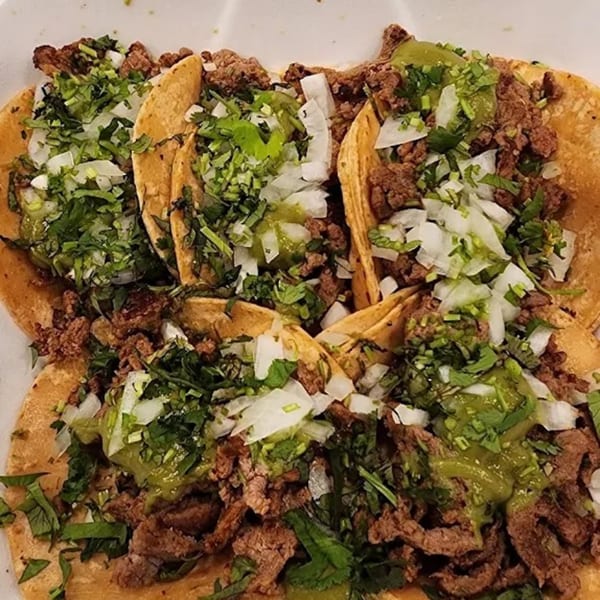 Four Sayulitas Mexican street tacos with carne asada, onions, cilantro, and green salsa.